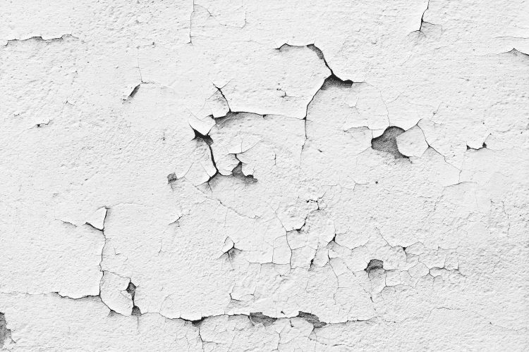 Witte verf van een muur vol barsten bladdert af.