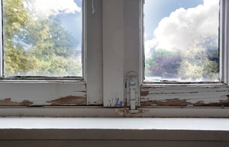 De verf van het houten raam is oud, gebarsten en aan het loslaten.

